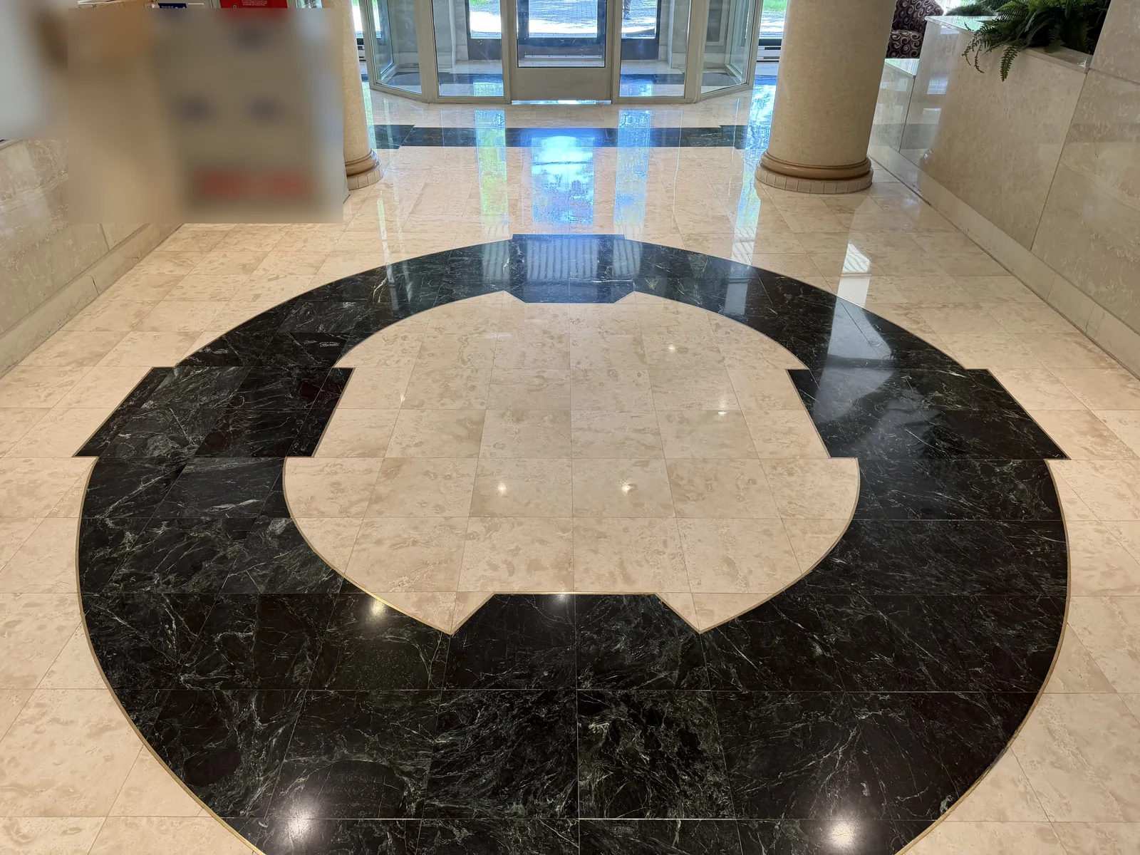 Restored marble lobby floor with a green marble circular inlay in Pierrefonds, privacy-edited